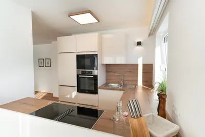 Küche mit Kochinsel, Holztheke und Barhockern im Apartment