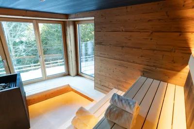 Sauna mit Holzbänken und großen Fenstern ins Grüne